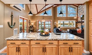A spacious kitchen with a large island, wooden cabinets, and a view of the outdoors.