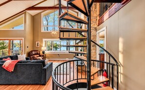 A spacious living area with a modern staircase, a leather sofa, and a view of the outdoors.