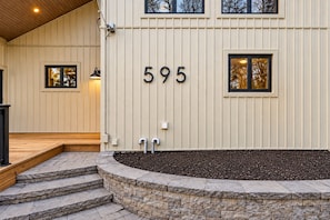 A building with a beige exterior, a stone staircase leading to a wooden deck, and the number 595 displayed on the wall.