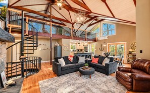 A spacious living area with a staircase leading to an upper level, a kitchen, and a dining area.