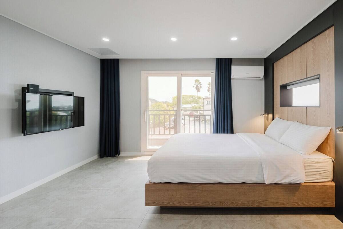 A modern bedroom with a bed, a TV, and an air conditioning unit.