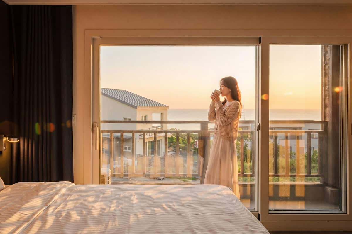A bedroom with a bed, a window, and a balcony.