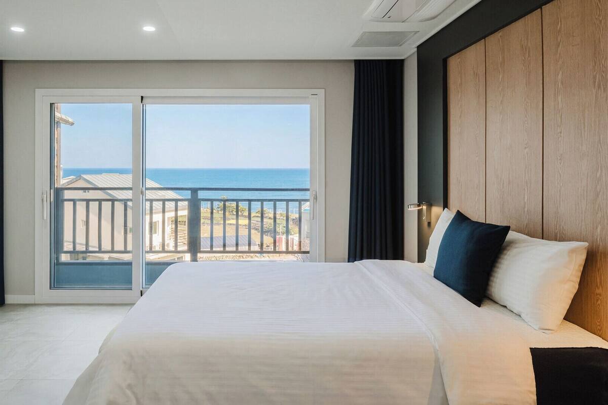 A hotel room with a large bed, a view of the ocean, and a balcony.