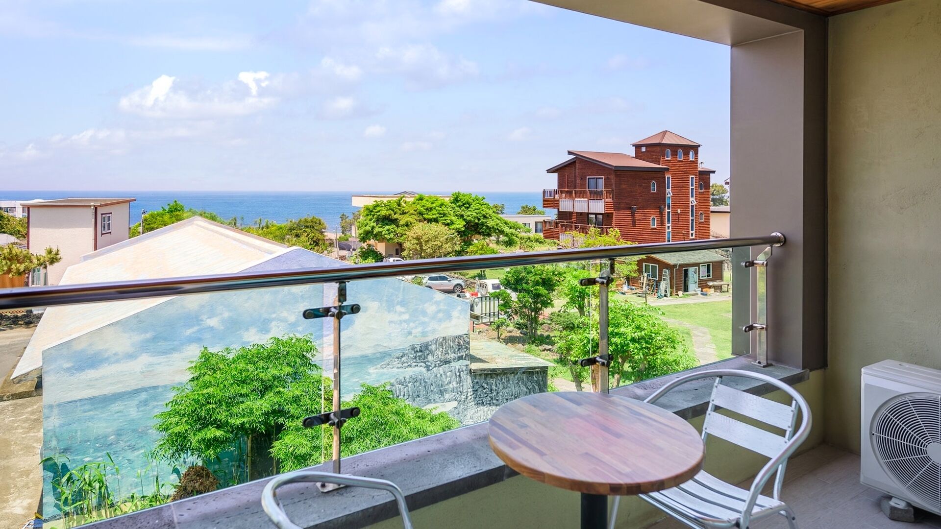 Un balcón con vistas al mar, una mesa, sillas y un equipo de aire acondicionado.
