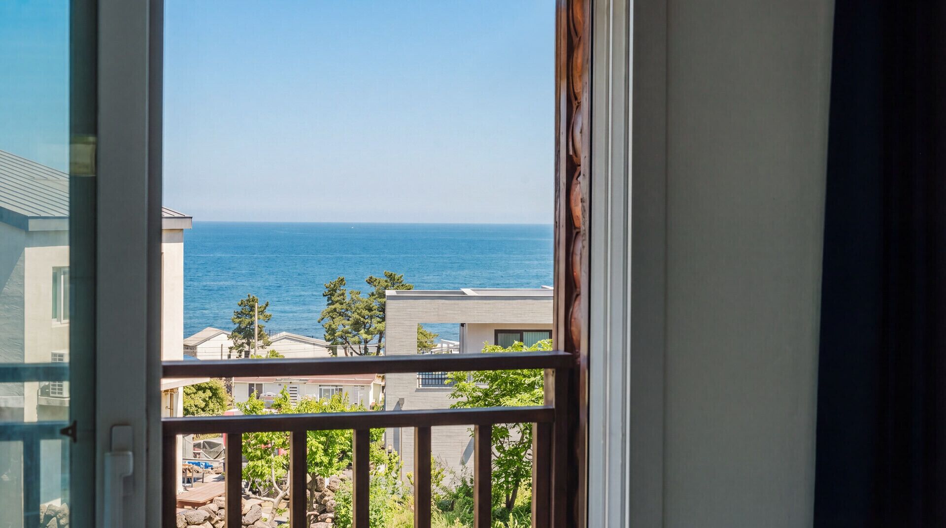 A balcony with a view of the sea and neighboring buildings.
