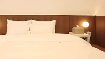 A neatly made bed with white linens, a bedside table with a lamp, and a tissue box.