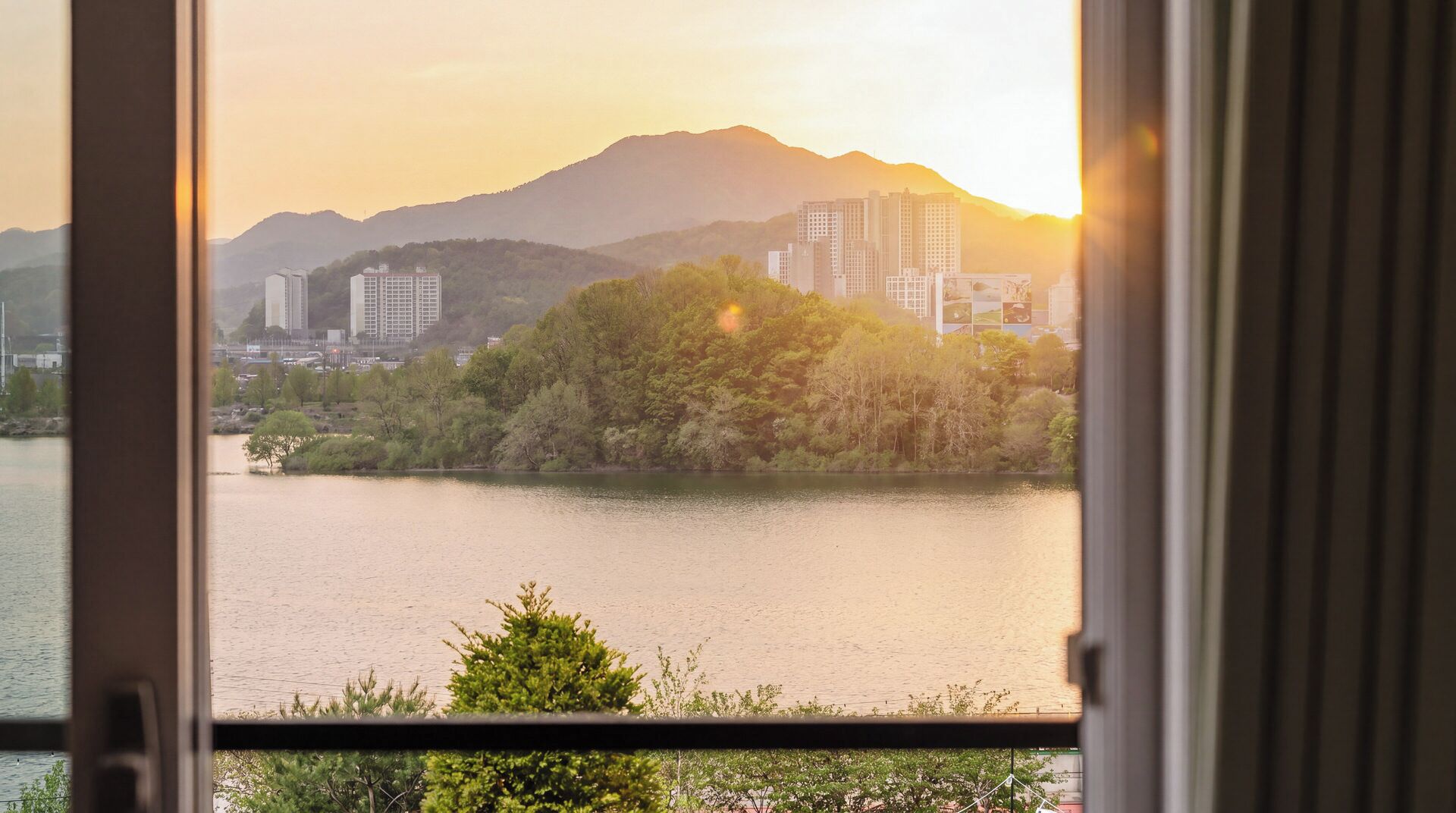 A view of a lake with buildings and mountains in the background.