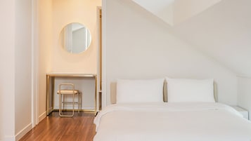 A bedroom with a bed, a bedside table, a chair, a mirror, and a door.