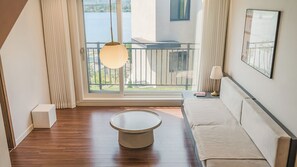 A modern hotel room with a wooden floor, a round coffee table, a sofa, a balcony with a view of the water, and a hanging lamp. - Chuncheon Rehouse (Chuncheon)