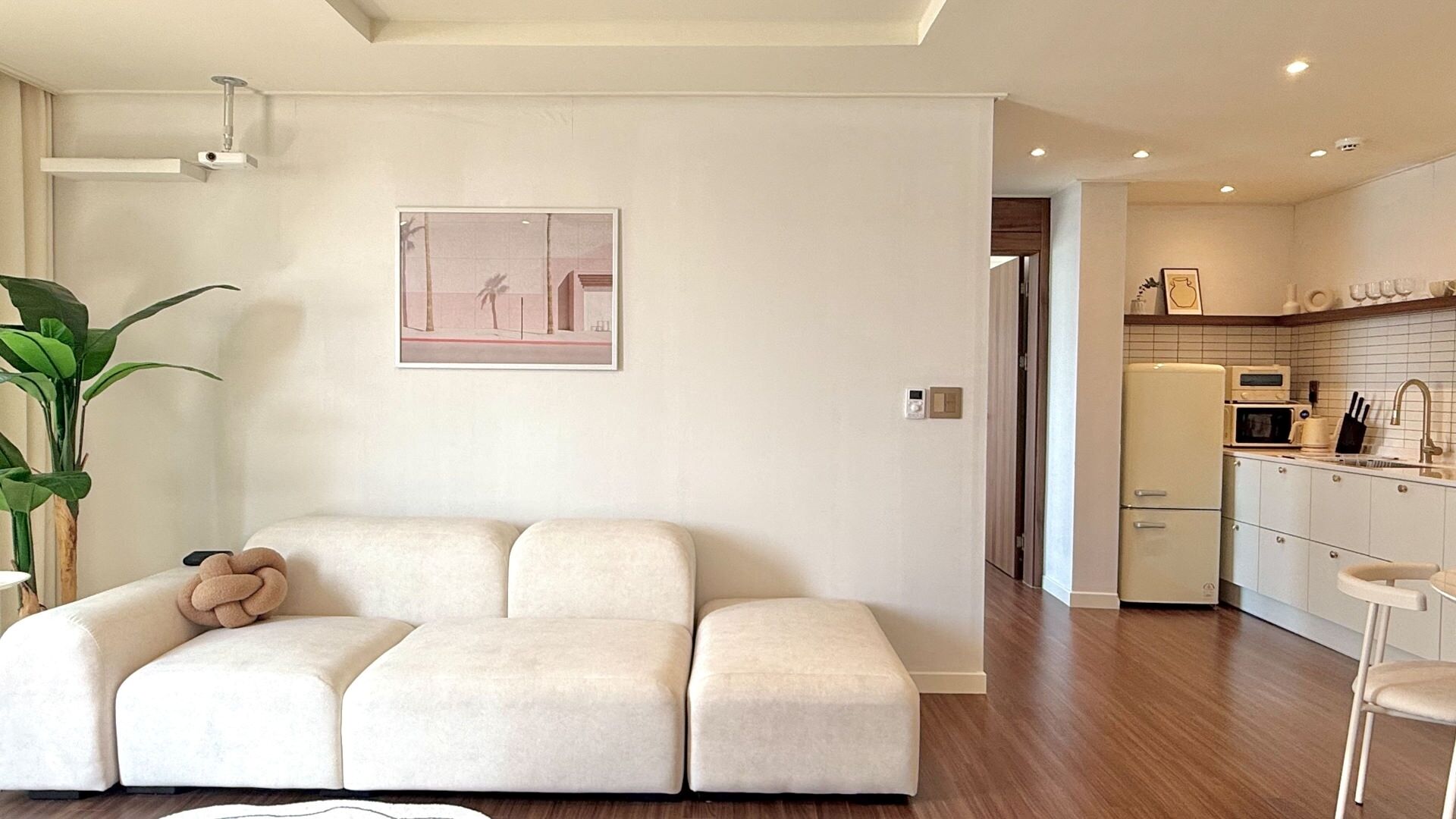 A modern living room with a sofa, a potted plant, and a framed picture on the wall.