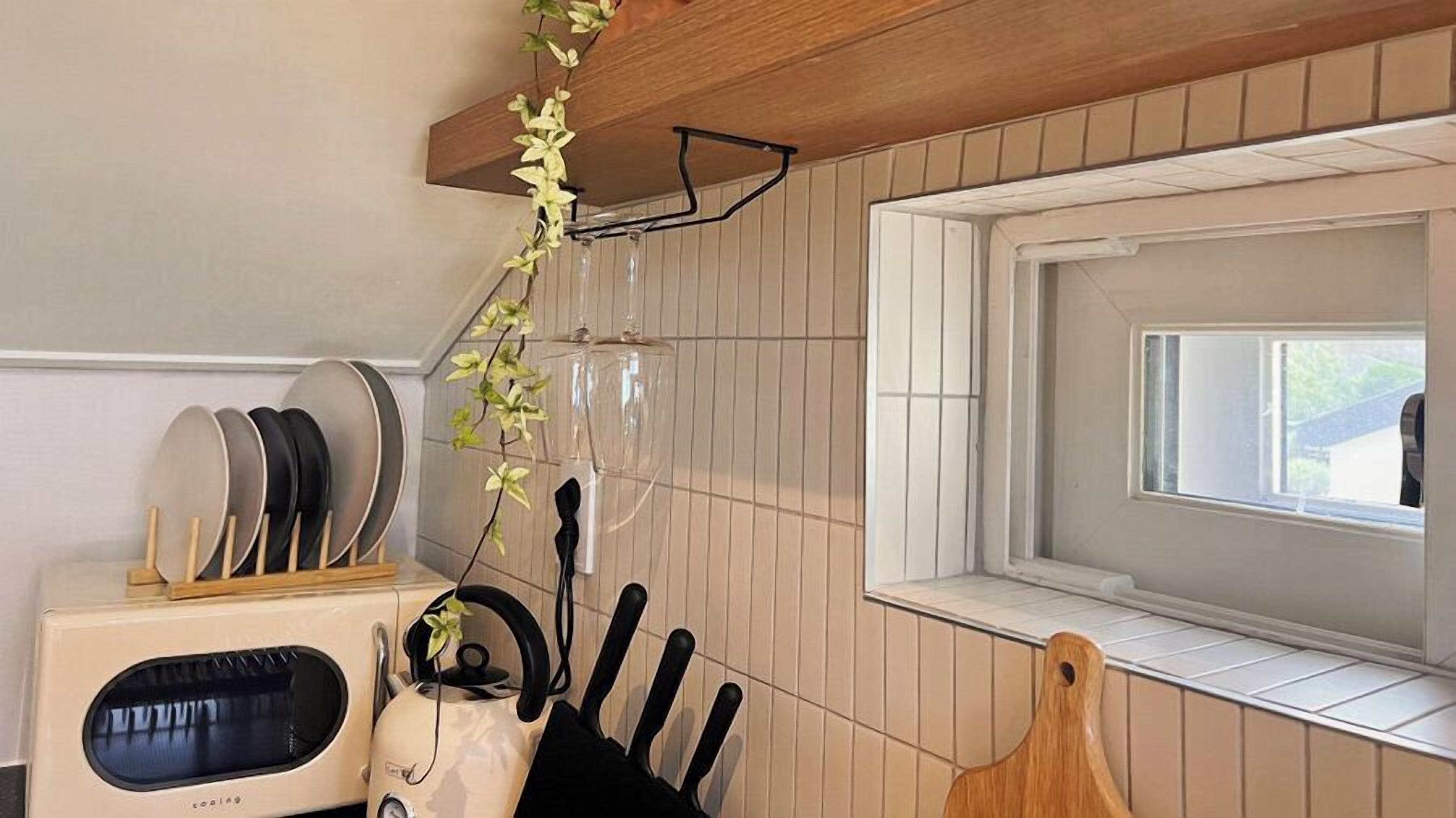 A kitchen with a microwave, knives, and a hanging plant.