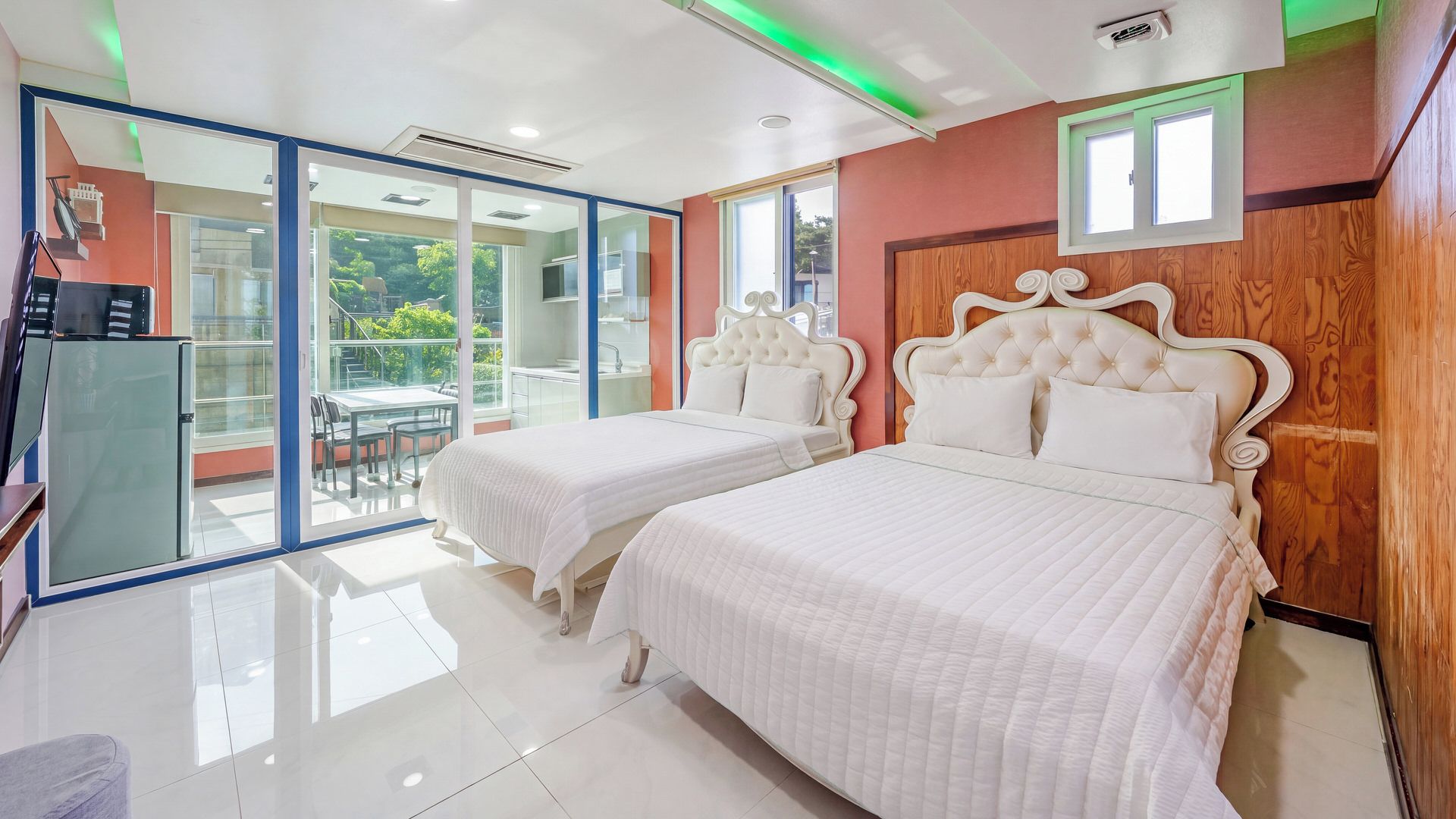 A hotel room with two beds, a balcony, and a view of the outdoors.