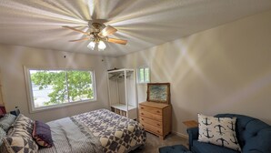 Quarto com cama, cómoda, cadeira e ventoinha no teto.