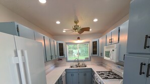 Uma cozinha moderna com ilha central, eletrodomésticos brancos e armários azuis.