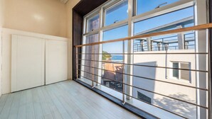 A room with a large window, a white door, and a view of the sea and buildings. - Geoje Erion Pet-friendly Pension (Geoje)