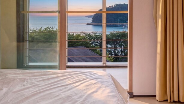 A bedroom with a large window, a bed, and curtains. - Geoje Erion Pet-friendly Pension (Geoje)