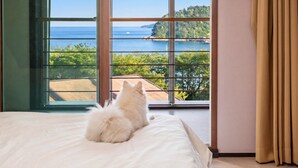 A room with a large window, a bed, and a view of the sea. - Geoje Erion Pet-friendly Pension (Geoje)