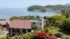 A coastal building with a view of the sea and hills. - Geoje Erion Pet-friendly Pension (Geoje)
