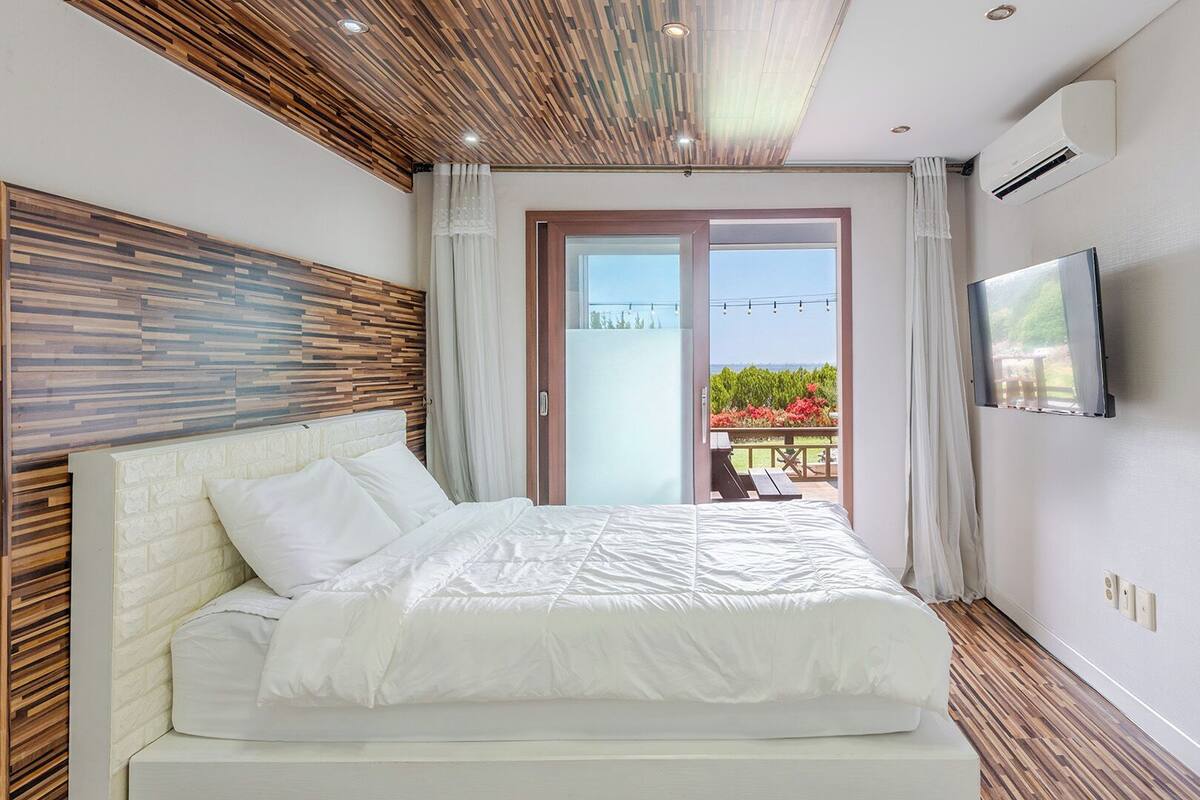 Un dormitorio con cama, televisión y balcón con vistas.
