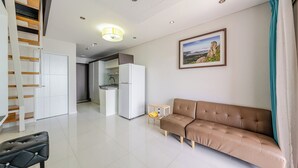 A modern living room with a sofa, a dining area, a kitchen, and a staircase. - Geoje Pings Pet-friendly Pension (Geoje)