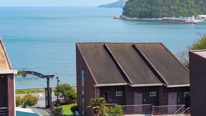 A coastal hotel with a pool, a view of the sea, and a rocky island in the background. - Geoje Pings Pet-friendly Pension (Geoje)
