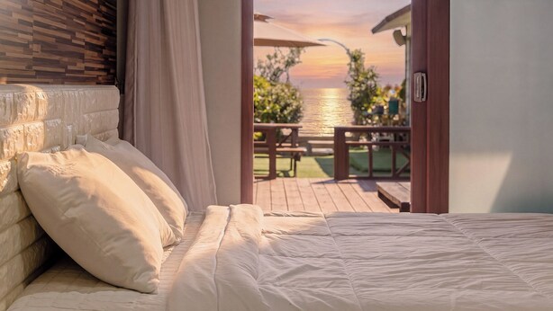 A bedroom with a view of a wooden deck and a body of water. - Geoje Pings Pet-friendly Pension (Geoje)