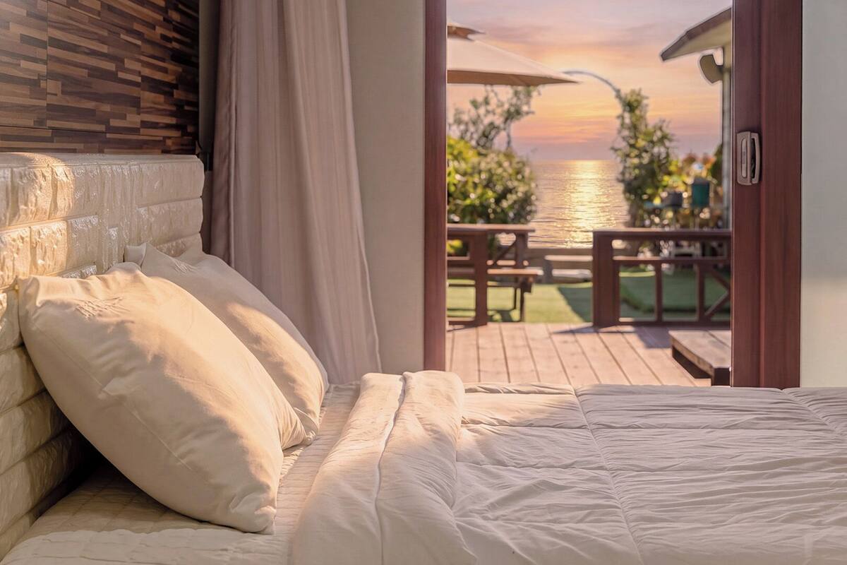 Un dormitorio con vista a una terraza de madera y una masa de agua.