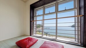 A room with a large window, a wooden floor, and two red cushions. - Geoje Pings Pet-friendly Pension (Geoje)