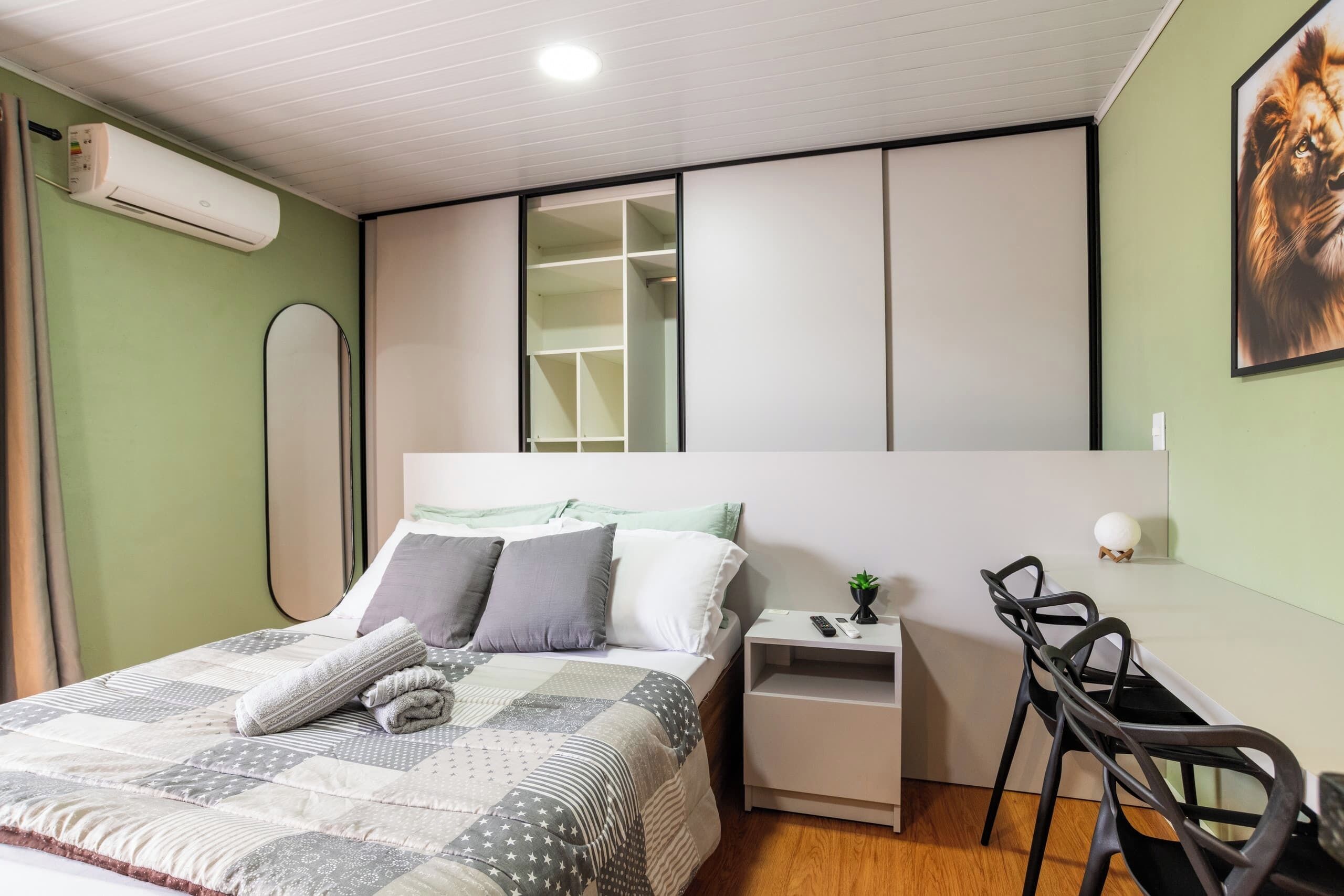Une chambre à coucher comprenant un lit, une table de chevet, une chaise et une armoire avec des portes coulissantes.
