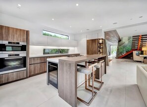 Una cocina moderna con una isla central, electrodomésticos integrados y vistas al verdor.