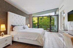 Un dormitorio moderno con una cama grande, una mesita de noche, un escritorio y un televisor.