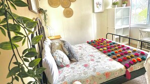 Ein Schlafzimmer mit einem Bett, einem Deckenventilator, einem Fenster mit Blick und einer Pflanze.