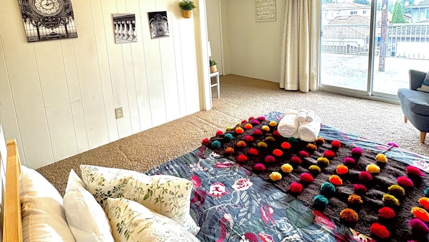 Ein Schlafzimmer mit Bett, Kissen, einem Fenster und einer Tür zu einem anderen Raum.