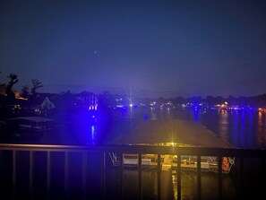 Ein beleuchtetes Ufergebiet bei Nacht mit Gebäuden und einem Steg.