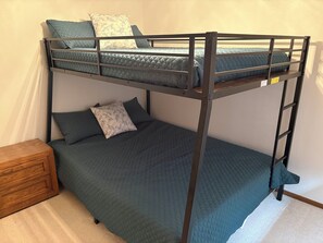 Ein Etagenbett mit einem Holfnachtkästchen und einem kleinen Holzschrank.