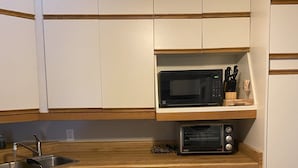 A kitchen with white cabinets, a microwave, a toaster, and a wooden countertop. - Family Friendly Cottage close to beach and main strip. (Grand Bend)
