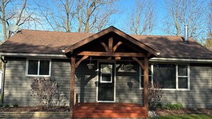 A house with a covered porch, a chimney, and a satellite dish. - Family Friendly Cottage close to beach and main strip. (Grand Bend)