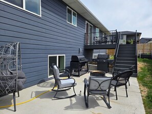 Eine Terrasse mit Gartenmöbeln, einem Grill und einer Rutsche, die auf einen Balkon führt.
