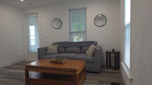 A living room with a grey sofa, a wooden coffee table, two round mirrors, and a small side table. - Main Haven- Spacious 4BR Retreat 9 min to All star Village 21 min to Cooperstown (Oneonta)