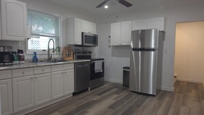 A modern kitchen with white cabinets, stainless steel appliances, and a herringbone-patterned floor. - Main Haven- Spacious 4BR Retreat 9 min to All star Village 21 min to Cooperstown (Oneonta)