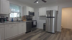 A modern kitchen with white cabinets, stainless steel appliances, and a herringbone-patterned floor.