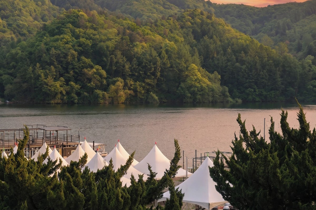 A lakeside view with tents and a dock.