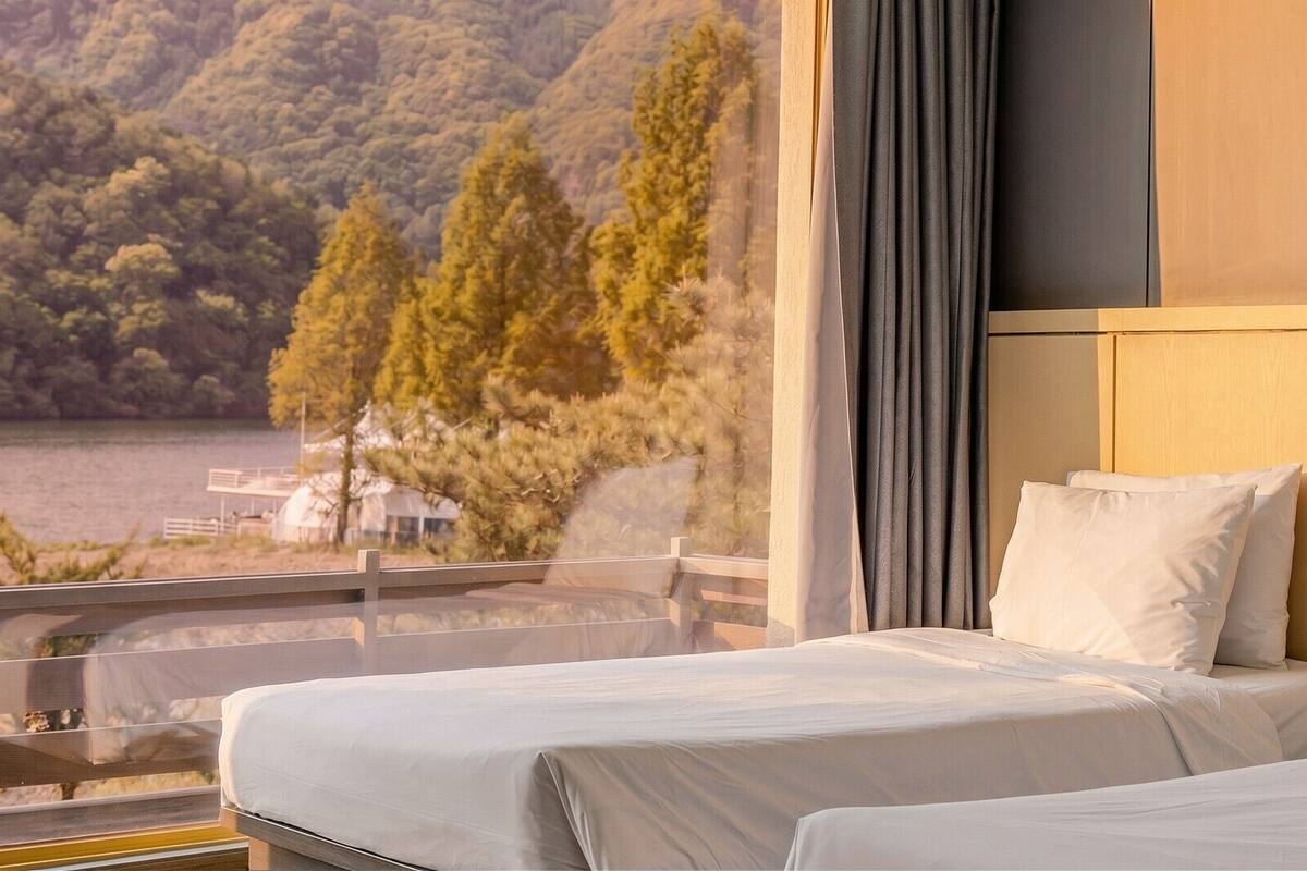 A hotel room with a bed, a view of a lake, and a balcony.