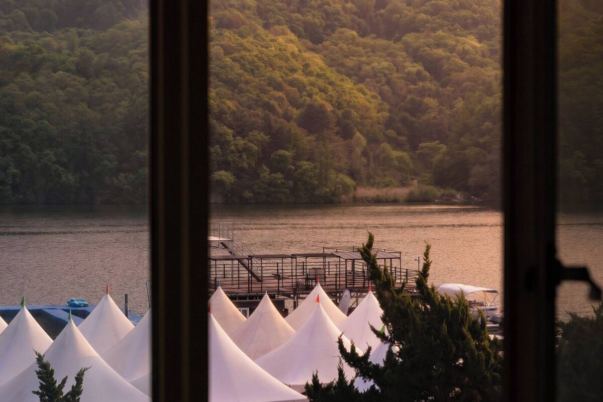 A lakeside view with tents and a dock.