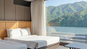 Une chambre d’hôtel avec un lit, une table de chevet et une vue sur un lac et des montagnes.