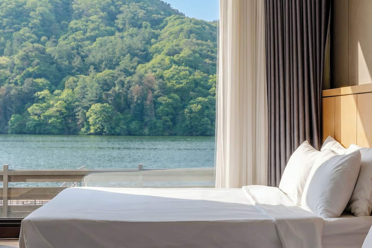 A bedroom with a large bed, a view of a lake, and a mountain in the background.