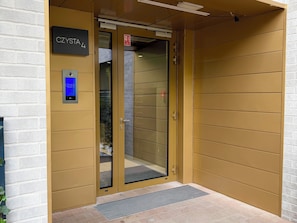 An elevator entrance with a digital display, a glass door, and a metal door handle. - Czysta Bright Studio (Wrocław)