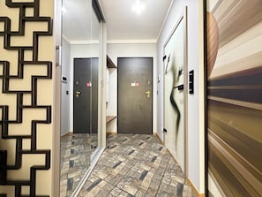 A hallway with a patterned floor, a mirrored wall, and doors with keypads. - Czysta Bright Studio (Wrocław)