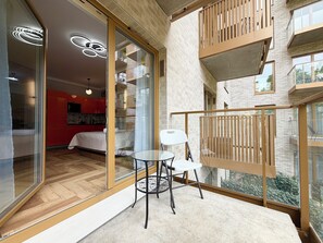 A modern apartment with a balcony, a dining area, and a bedroom with a red accent wall. - Czysta Bright Studio (Wrocław)