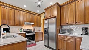 A kitchen with wooden cabinets, stainless steel appliances, and a granite countertop. - Peaceful perfection! 4-bedroom mountain lake house on Lake Adger. Near Lake Lure (Mill Spring)